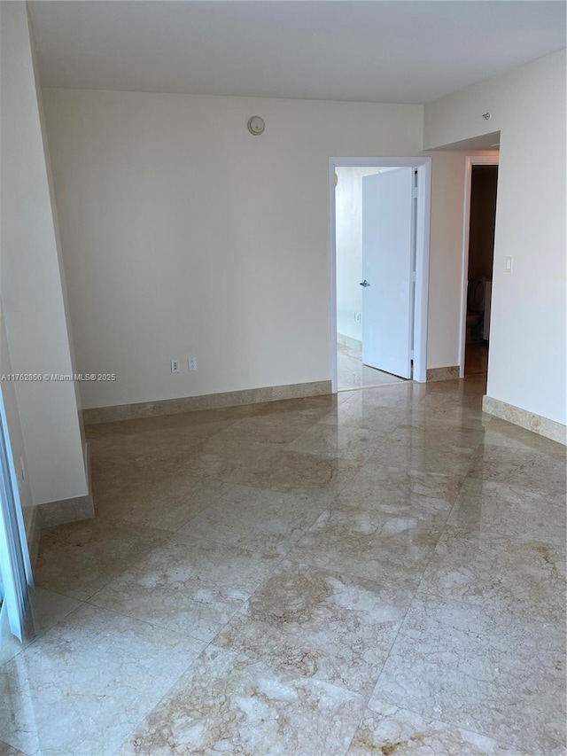 spare room featuring baseboards and marble finish floor