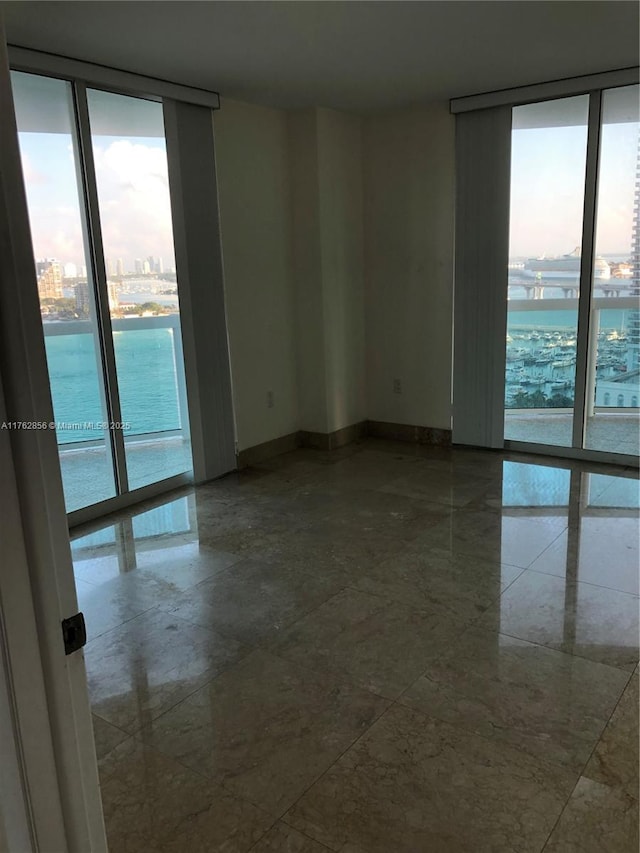 spare room featuring a wall of windows, baseboards, and a view of city