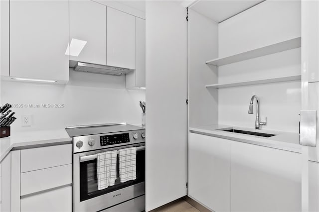 kitchen featuring open shelves, under cabinet range hood, stainless steel range with electric stovetop, white cabinets, and a sink