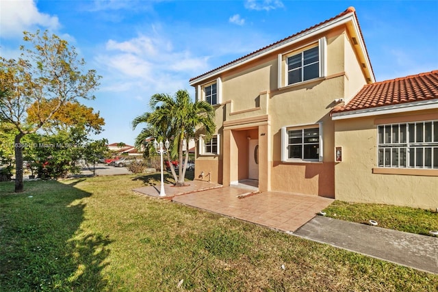 back of property featuring stucco siding, a yard, and a tiled roof