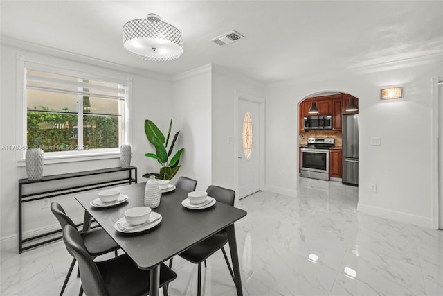 dining room with visible vents, baseboards, ornamental molding, arched walkways, and marble finish floor