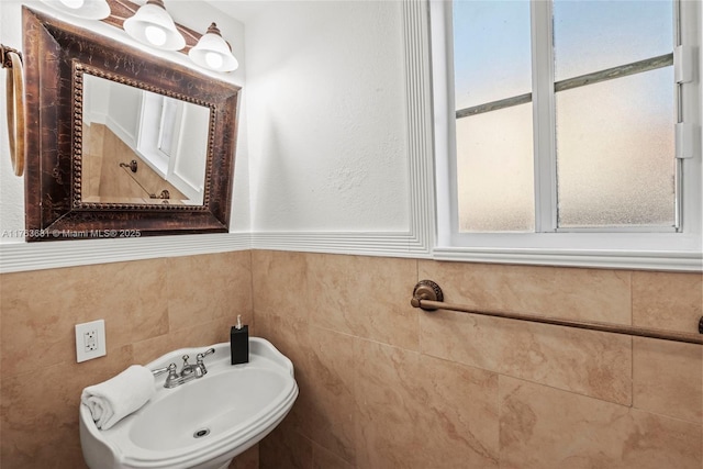 bathroom with a wainscoted wall, tile walls, and a sink