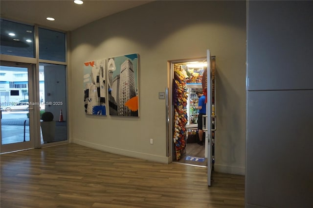 corridor featuring recessed lighting, a wall of windows, baseboards, and wood finished floors