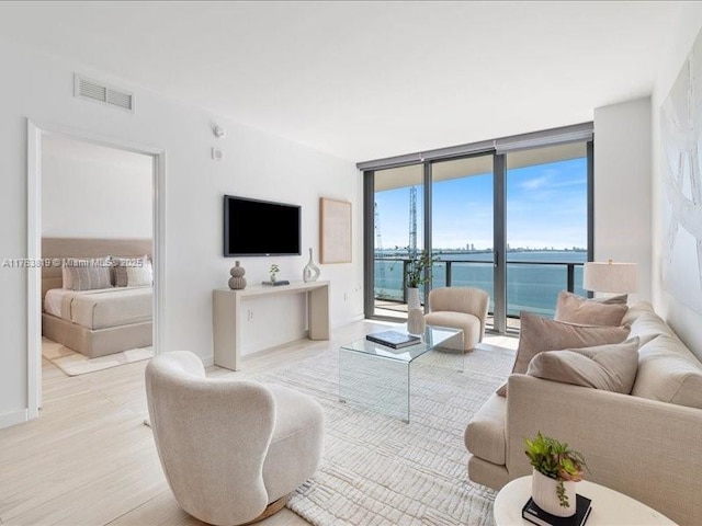 living area featuring light wood-style flooring, visible vents, and expansive windows