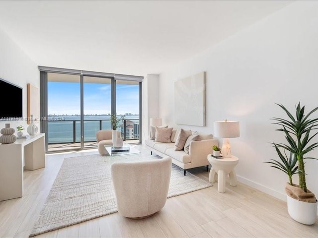 living area featuring light wood finished floors, baseboards, and expansive windows