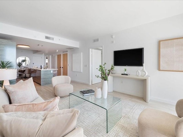 living room featuring visible vents, light wood-style floors, and baseboards