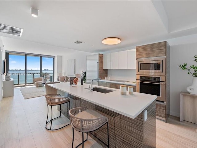 kitchen with visible vents, radiator heating unit, a sink, stainless steel appliances, and a kitchen bar