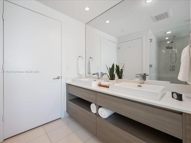 full bathroom with visible vents, double vanity, a stall shower, a sink, and tile patterned floors