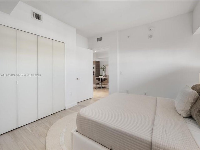 bedroom featuring a closet, light wood-style floors, and visible vents