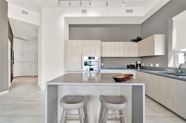 kitchen with light brown cabinetry, visible vents, modern cabinets, and a kitchen bar