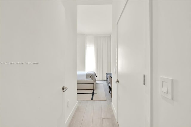 hall with light wood-style flooring and baseboards