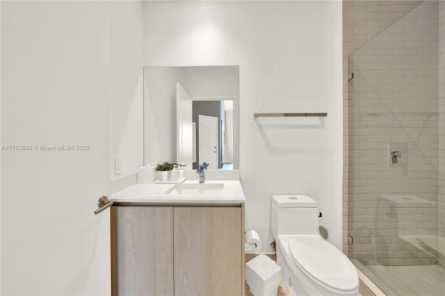 bathroom featuring vanity, toilet, and tiled shower