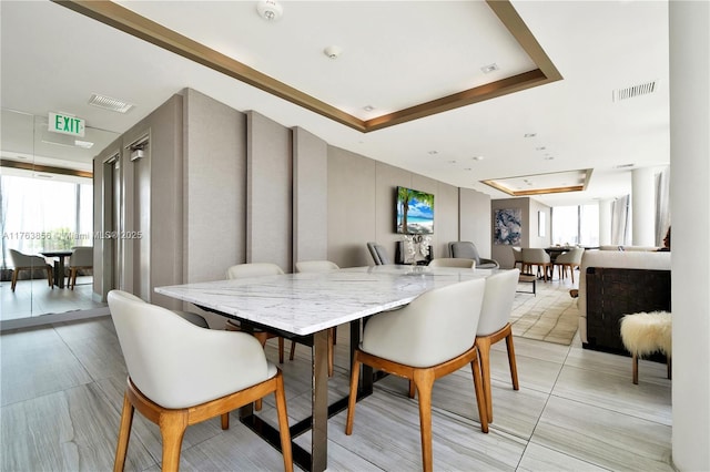 dining area with a tray ceiling and visible vents