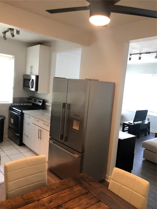 kitchen with plenty of natural light, appliances with stainless steel finishes, white cabinets, and light countertops