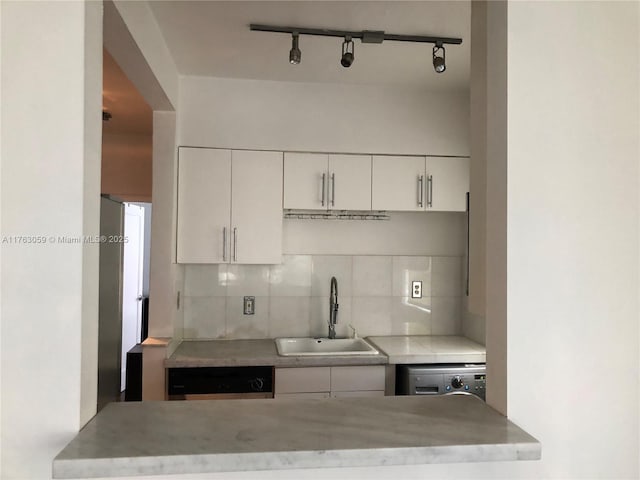 kitchen featuring decorative backsplash, white cabinetry, and a sink