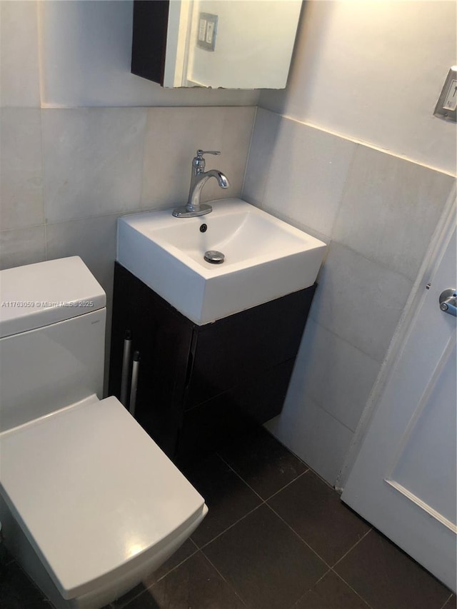 half bath featuring tile patterned floors, toilet, tile walls, and vanity