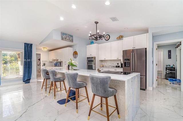 kitchen featuring marble finish floor, appliances with stainless steel finishes, white cabinets, and vaulted ceiling