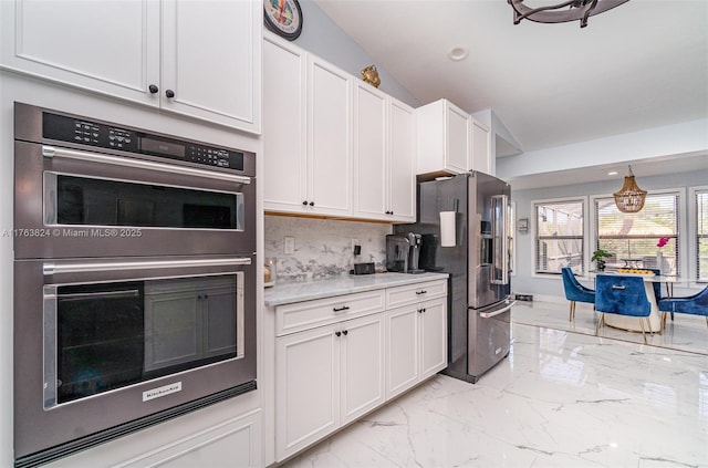 kitchen featuring light countertops, vaulted ceiling, appliances with stainless steel finishes, white cabinetry, and marble finish floor