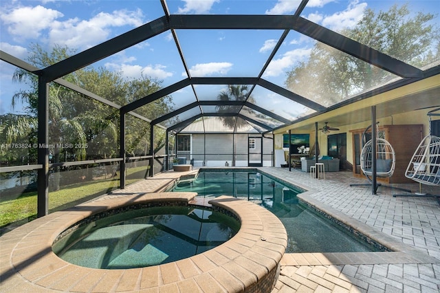 view of swimming pool with glass enclosure, a pool with connected hot tub, a patio, and a ceiling fan