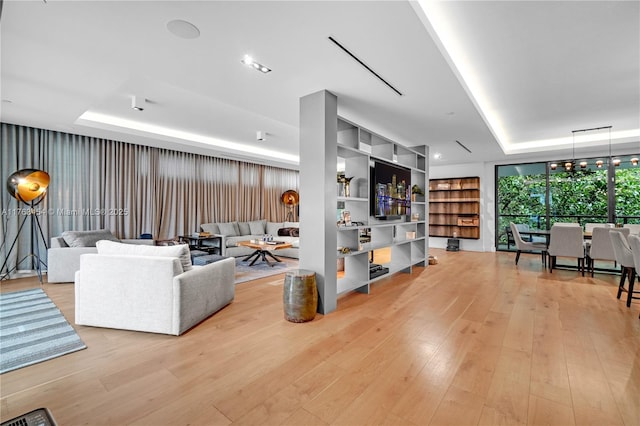 living area featuring expansive windows, a raised ceiling, and light wood-style floors