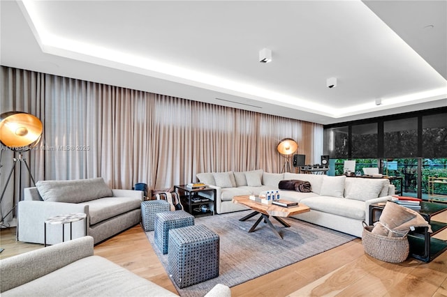 living room with a tray ceiling and wood finished floors