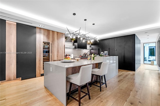 kitchen featuring light wood finished floors, light countertops, pendant lighting, modern cabinets, and dark cabinets