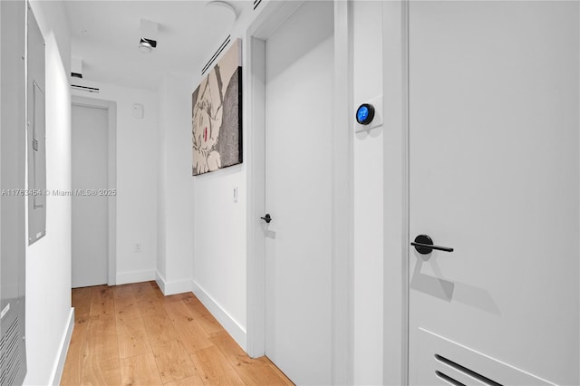 hall featuring light wood-style flooring and baseboards