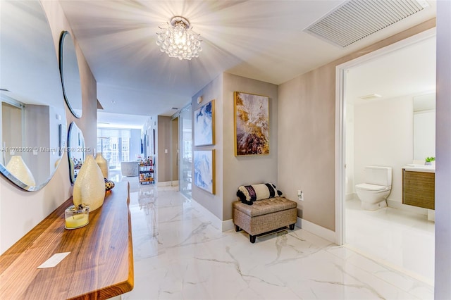 hallway with visible vents, marble finish floor, baseboards, and an inviting chandelier