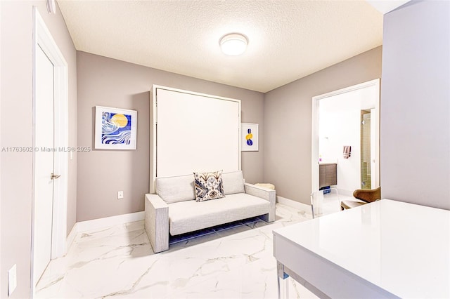 bedroom featuring ensuite bath, marble finish floor, a textured ceiling, and baseboards