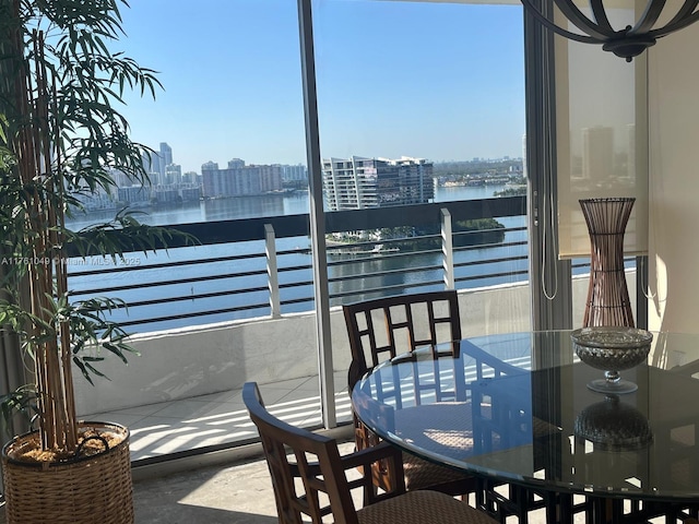 balcony featuring a city view, outdoor dining area, and a water view