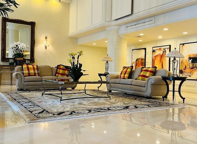 living area with decorative columns, marble finish floor, and a towering ceiling