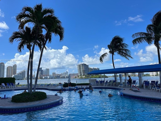 pool with a patio, a view of city, fence, and a water view