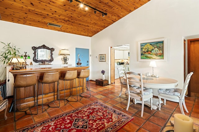 tiled dining room featuring visible vents, high vaulted ceiling, track lighting, washing machine and dryer, and wooden ceiling