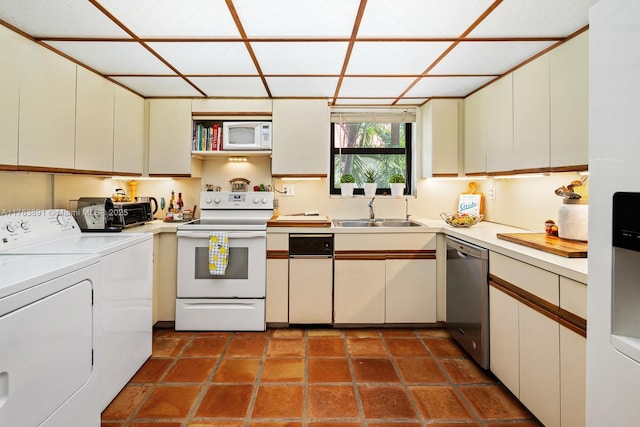 kitchen with white appliances, a sink, light countertops, dark tile patterned floors, and independent washer and dryer