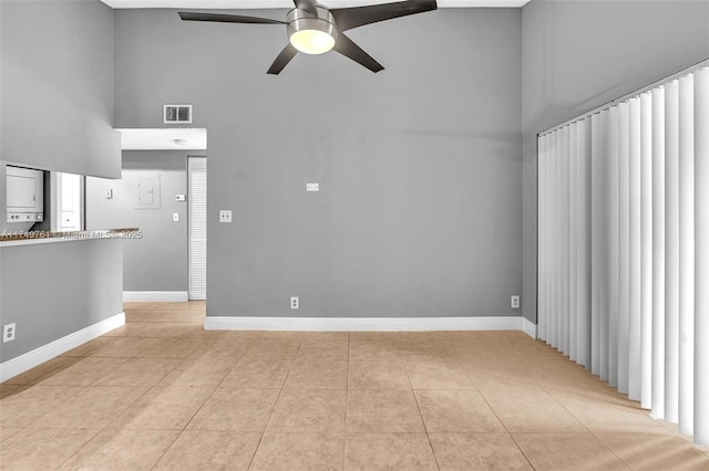 unfurnished living room with visible vents, a towering ceiling, light tile patterned floors, baseboards, and ceiling fan