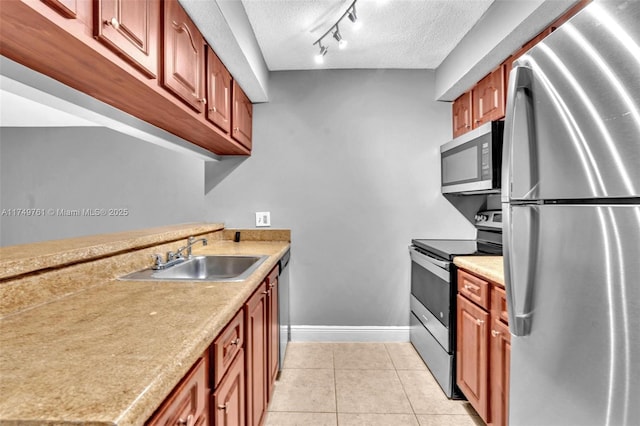 kitchen with light tile patterned floors, a sink, light countertops, appliances with stainless steel finishes, and a textured ceiling