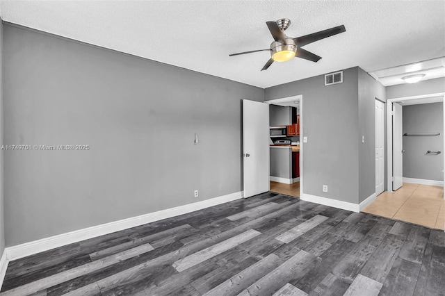 unfurnished bedroom featuring visible vents, ceiling fan, baseboards, wood finished floors, and a textured ceiling