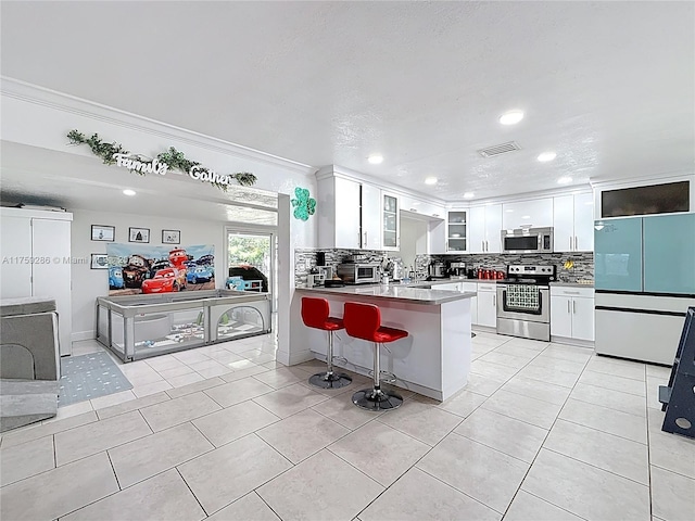 kitchen featuring visible vents, light tile patterned floors, decorative backsplash, appliances with stainless steel finishes, and white cabinetry