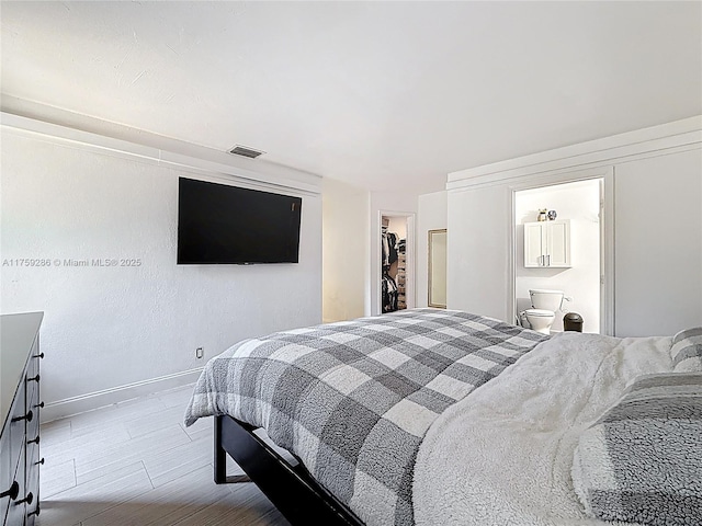 bedroom featuring wood finished floors, visible vents, baseboards, a closet, and a walk in closet