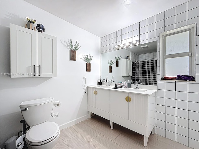 bathroom featuring double vanity, toilet, baseboards, and a sink