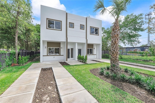 view of front facade with a front lawn, fence, and stucco siding