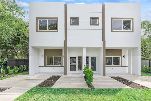 back of property with stucco siding, french doors, and fence