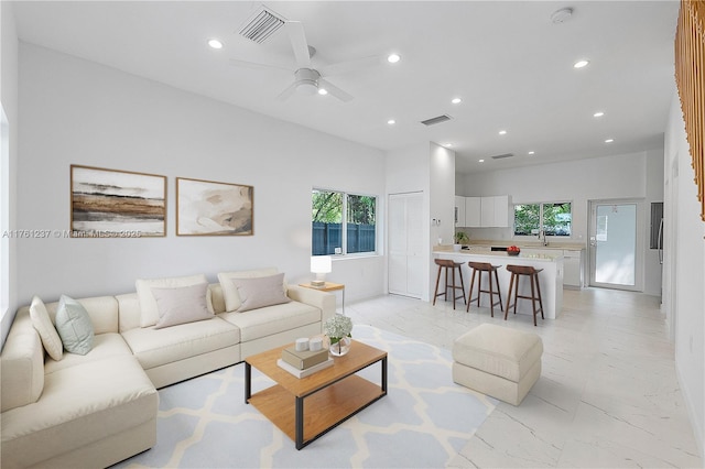 living area with recessed lighting, visible vents, marble finish floor, and a healthy amount of sunlight