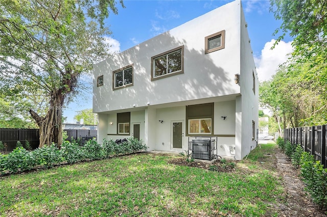 back of house featuring stucco siding, a yard, and a fenced backyard