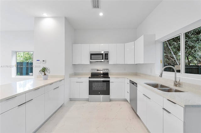 kitchen featuring visible vents, white cabinets, marble finish floor, stainless steel appliances, and a sink