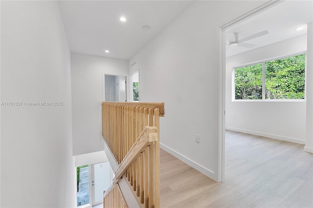 hallway with baseboards, an upstairs landing, a healthy amount of sunlight, and light wood finished floors