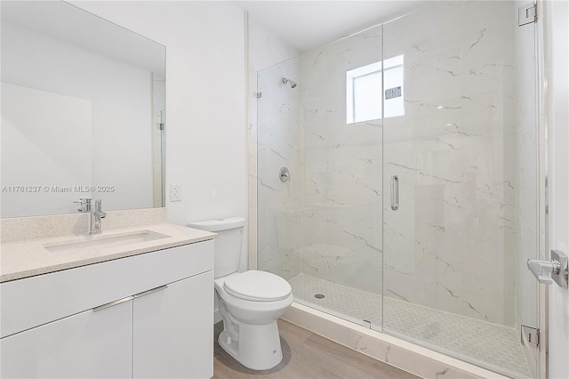 full bathroom featuring a marble finish shower, toilet, wood finished floors, and vanity