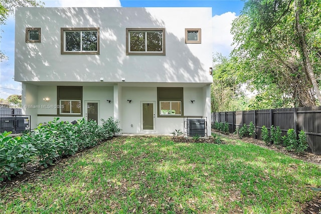 rear view of property featuring a yard, a fenced backyard, and stucco siding