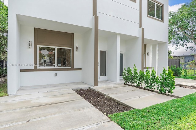 property entrance with fence and stucco siding