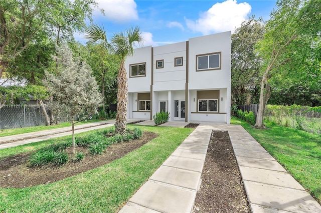 view of front of house featuring stucco siding, a front yard, and fence